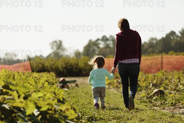 Mother and daughter holding hands in pumpkin field