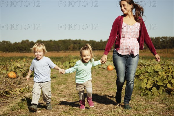 Mother with two children running in pumpkin field