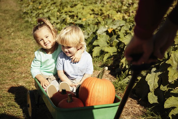 Brother and sister being pulled in pumpkin cart