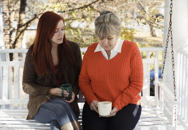 Senior woman and adult daughter having serious discussion on porch