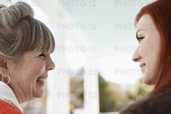 Close up of senior woman and adult daughter laughing on porch
