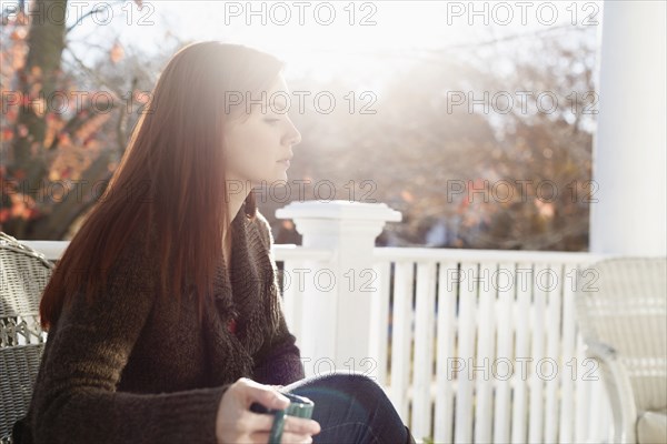 Young woman drinking coffee with eyes closed in porch