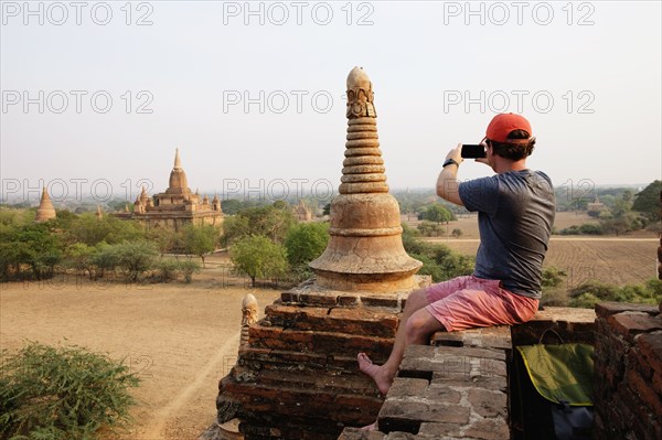 Man taking photograph from stone wall