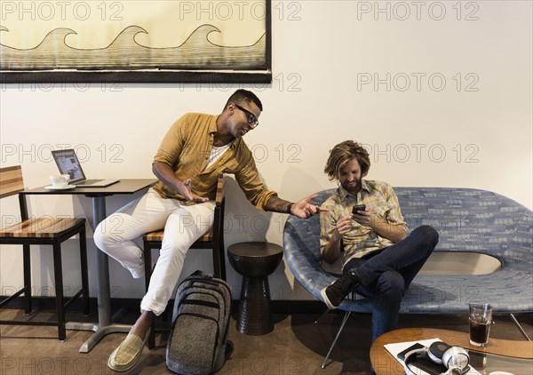 Two men in coffee shop using wireless technology