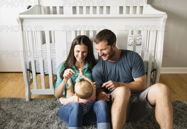 Mid adult couple playing with baby daughters fingers on lap