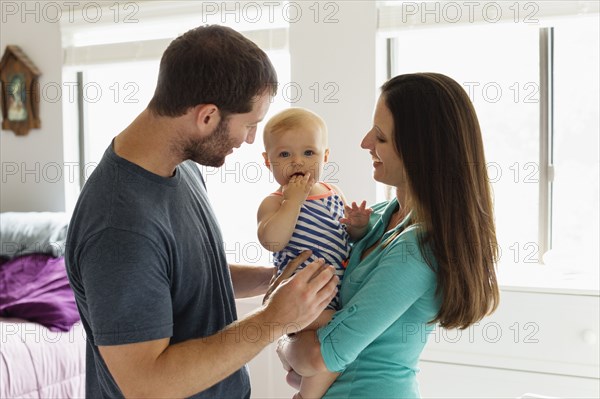 Portrait of mid adult couple with baby daughter in bedroom