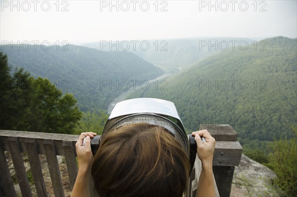 Mid adult woman looking through coin operated binoculars