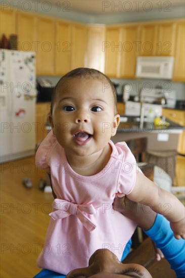 Portrait of baby girl in kitchen looking at camera smiling