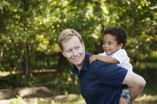 Side view of father giving son a piggyback smiling