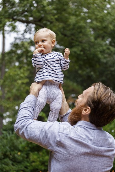 Father holding baby girl in air