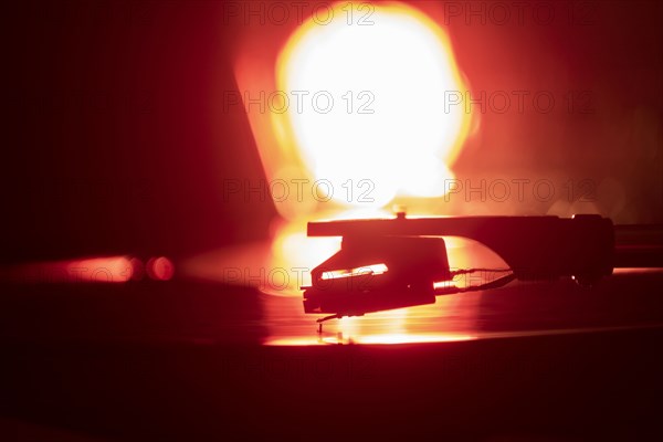 Close-up of a record player needle on record in orange light