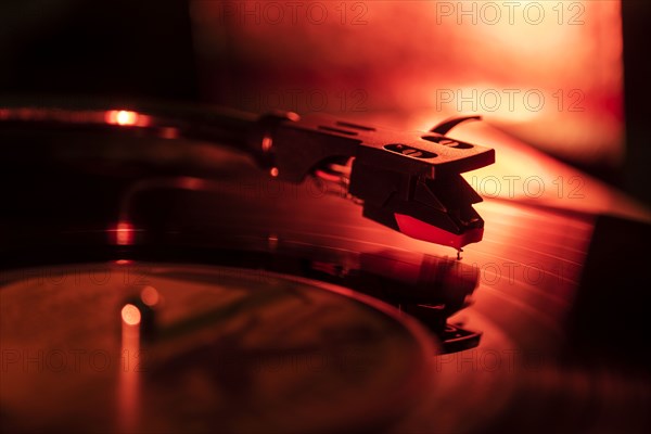 Close-up of a record player needle on record in red light