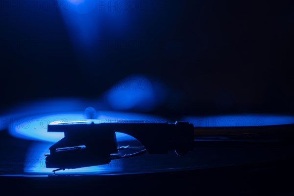 Close-up of a record player needle on record in blue light