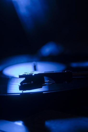 Close-up of a record player needle on record in blue light