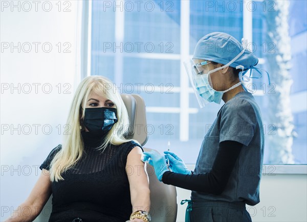 Woman in face mask receiving Covid-19 vaccination