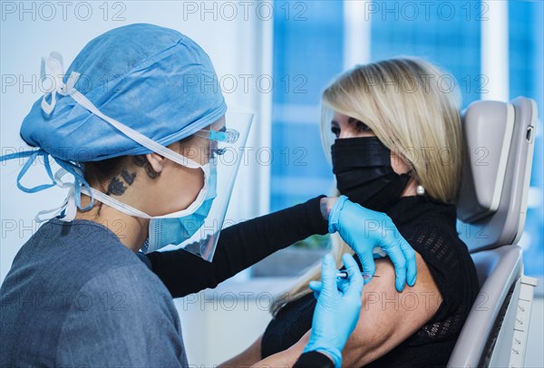 Woman in face mask receiving Covid-19 vaccination