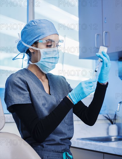 Nurse in face mask and shield preparing Covid-19 vaccination