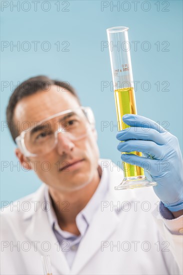 Scientist looking at yellow liquid in measuring beaker