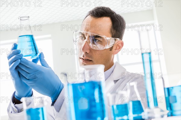 Scientist looking at blue liquid in laboratory