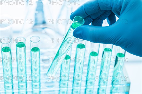 Gloved hand holding test tube with blue liquid