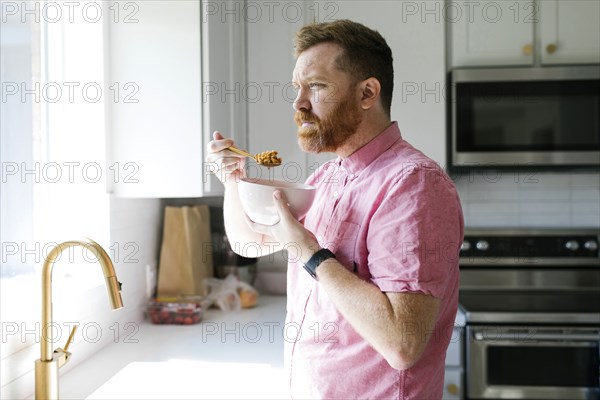 Man eating cereal in kitchen