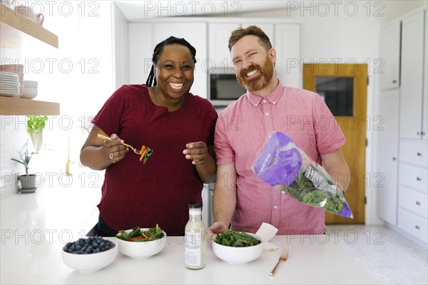 Smiling couple making salad in kitchen