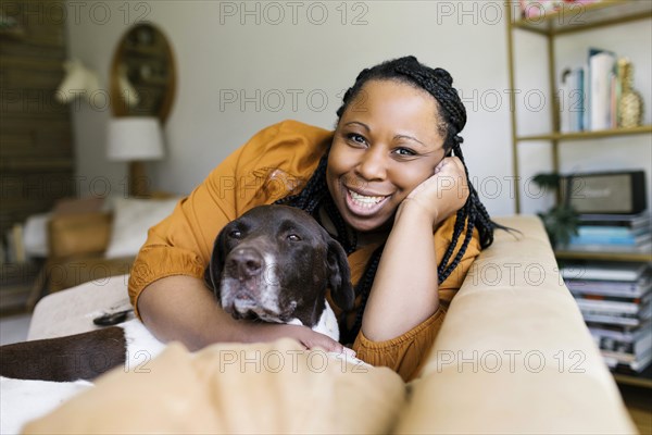 Smiling woman hugging dog on sofa