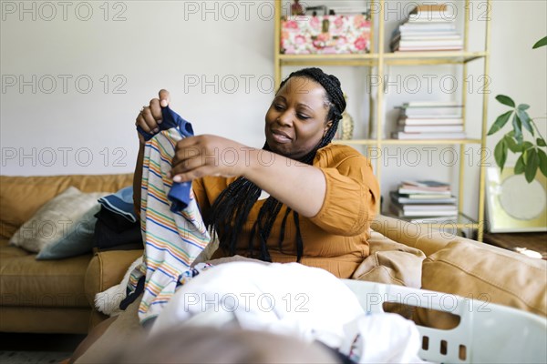 Woman sitting on sofa and folding laundry