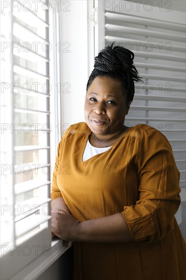 Portrait of smiling woman standing at window