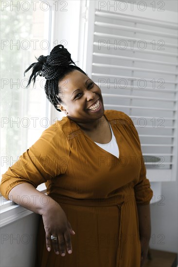 Portrait of smiling woman standing at window