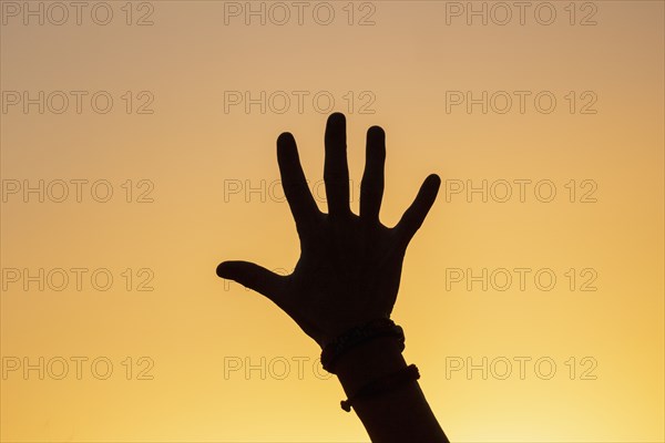 Silhouette of human hand against sunset sky