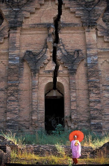 Buddhist nun in front of old Buddhist temple ruined by earthquake