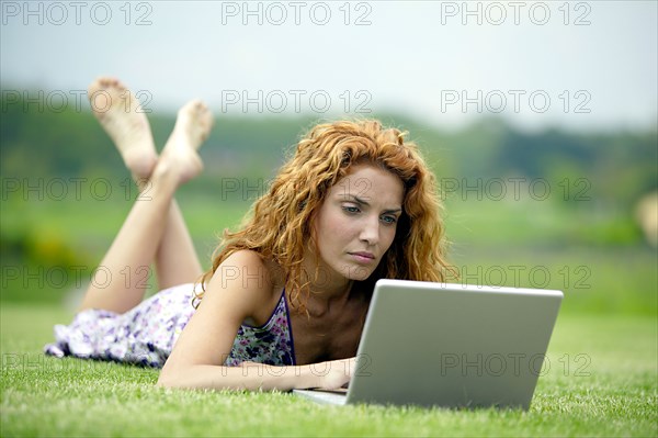 Woman with laptop on meadow
