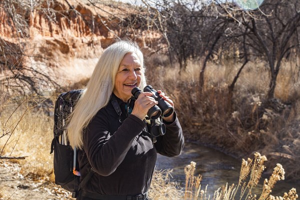 Senior woman uses binoculars while hiking in Grand Staircase-Escalante National Monument