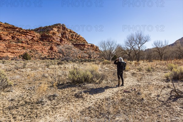 Woman using binoculars while hiking in Grand Staircase-Escalante National Monument