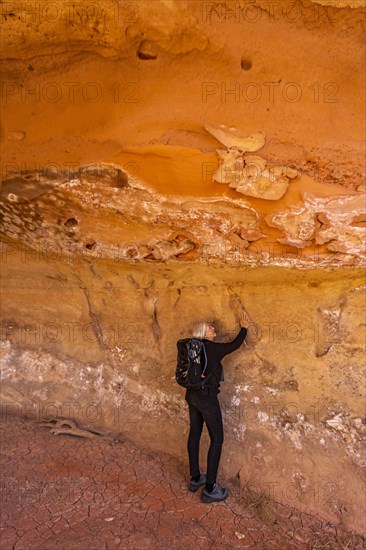 Woman touching sandstone cave wall in Grand Staircase-Escalante National Monument