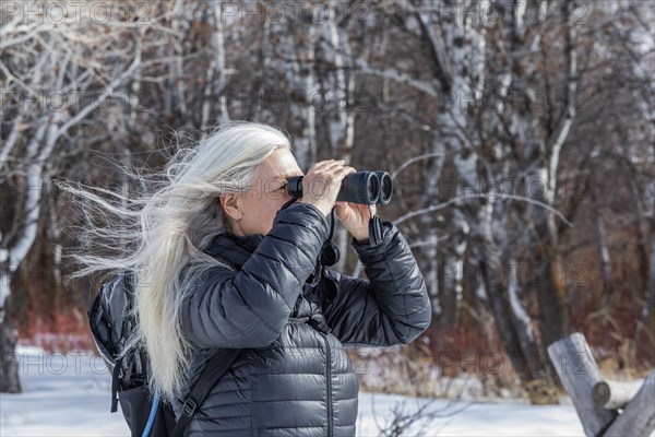 Senior woman using binoculars while hiking