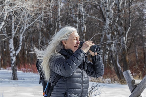 Senior woman using binoculars while hiking