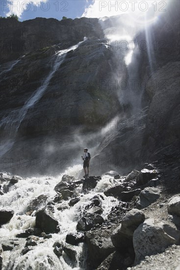 Man standing near Sofiyskiye Vodopady waterfall in Caucasus Mountains