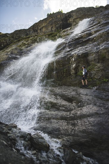 Man standing near Sofiyskiye Vodopady waterfall in Caucasus Mountains