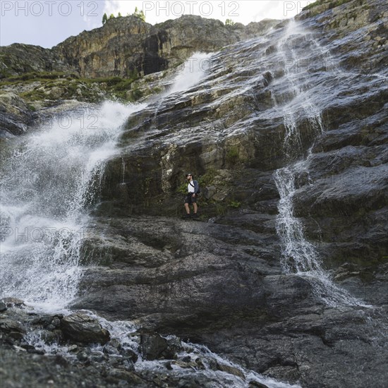 Man standing near Sofiyskiye Vodopady waterfall in Caucasus Mountains