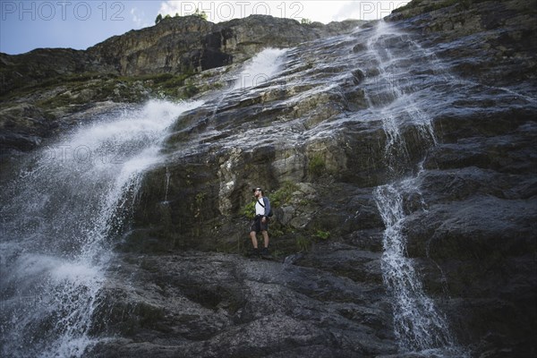 Man standing near Sofiyskiye Vodopady waterfall in Caucasus Mountains