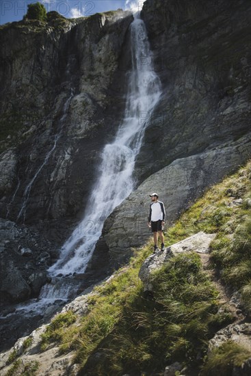 Man standing near Sofiyskiye Vodopady waterfall in Caucasus Mountains