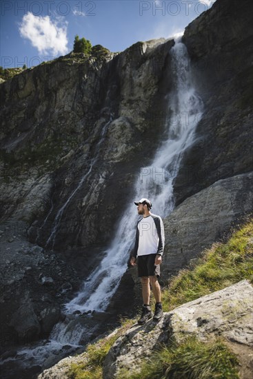 Man standing near Sofiyskiye Vodopady waterfall in Caucasus Mountains