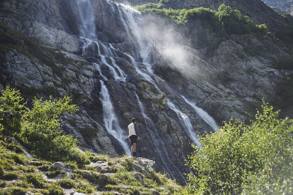 Man standing near Sofiyskiye Vodopady waterfall in Caucasus Mountains