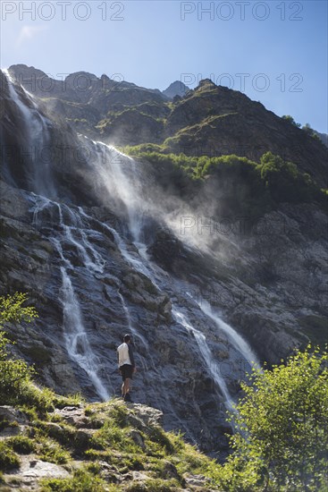 Man standing near Sofiyskiye Vodopady waterfall in Caucasus Mountains