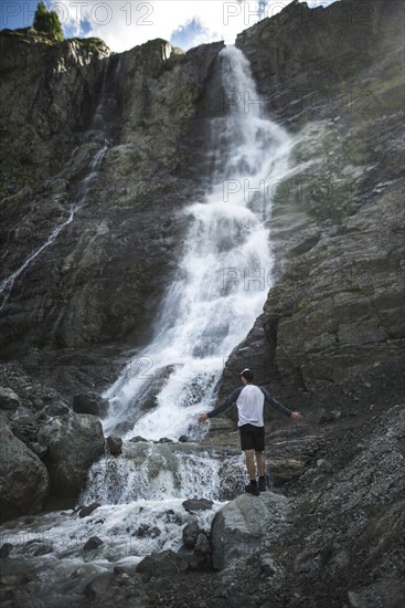 Man standing near Sofiyskiye Vodopady waterfall in Caucasus Mountains