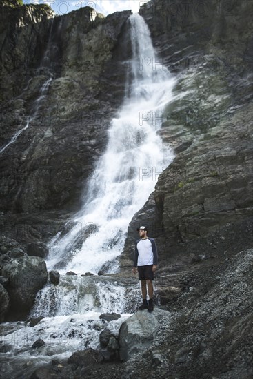 Man standing near Sofiyskiye Vodopady waterfall in Caucasus Mountains