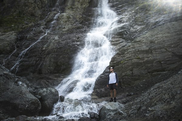 Man standing near Sofiyskiye Vodopady waterfall in Caucasus Mountains