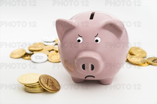 Angry Studio shot of pink piggy bank and bitcoins